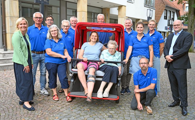 Stadtwerke-Geschäftsführer Tobias Koch (r.) überreichte die Spende in Höhe von 1.500 Euro an den Vorsitzenden des DRK-Ortsvereins, Jens Kümper (hinten, 4.v.r.), und das Ehrenamtlichen-Team. Die Empfänger und Bürgermeisterin Christina Rählmann (l.) freuten sich sehr über die Zuwendung. Zum Fototermin genossen Ursula Reckers (r.) und ihre Tochter Nicole Meyer eine kleine Ausfahrt mit der Rikscha. (Foto: SWTE)